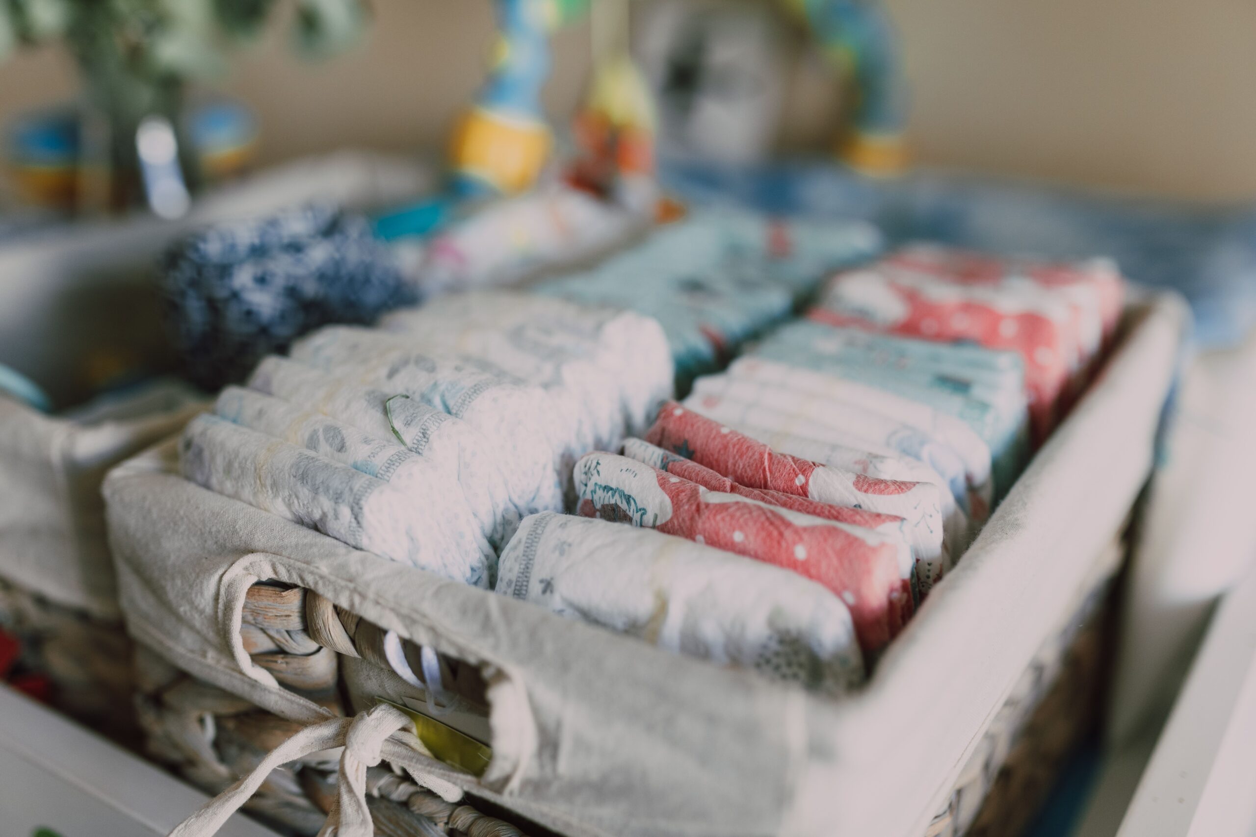 pexels photo 6849268 6849268 Close-up of neatly arranged colorful baby diapers in a woven basket, ideal for nursery organization.